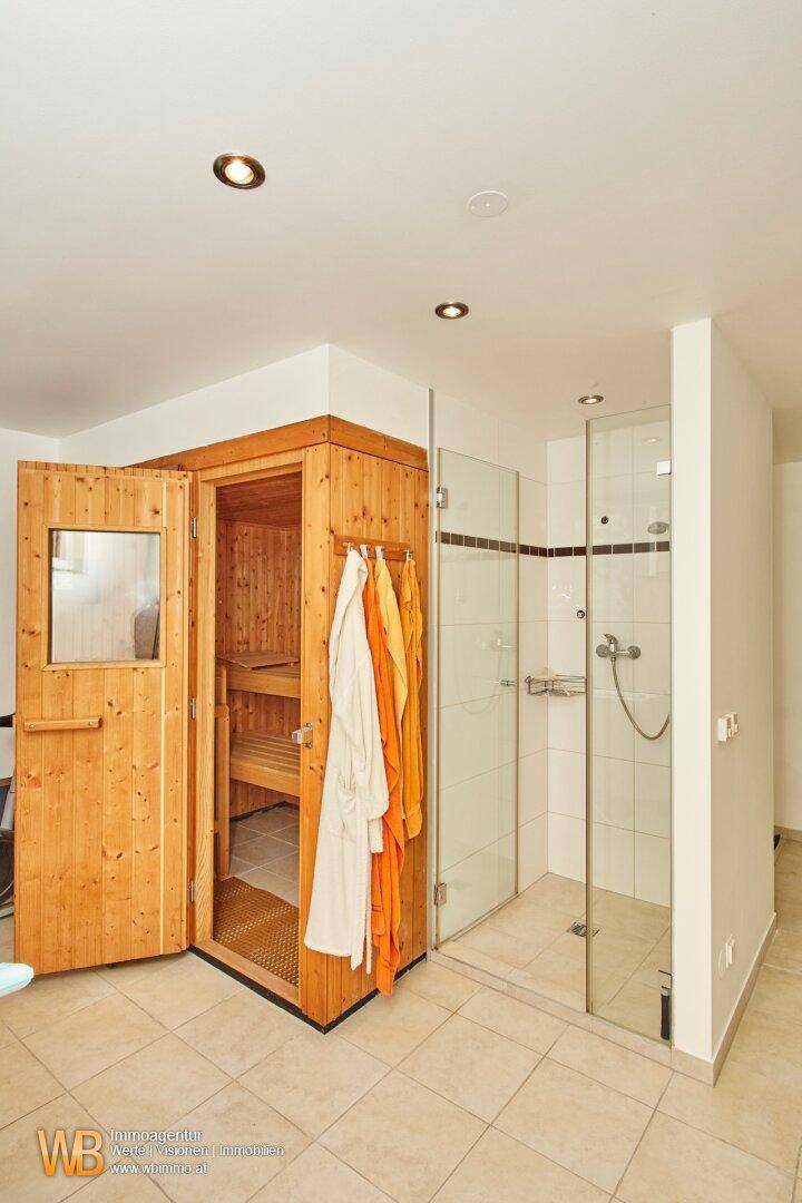 Privater Wellnessbereich mit holzvertäfelter Sauna und moderner Duschkabine.
