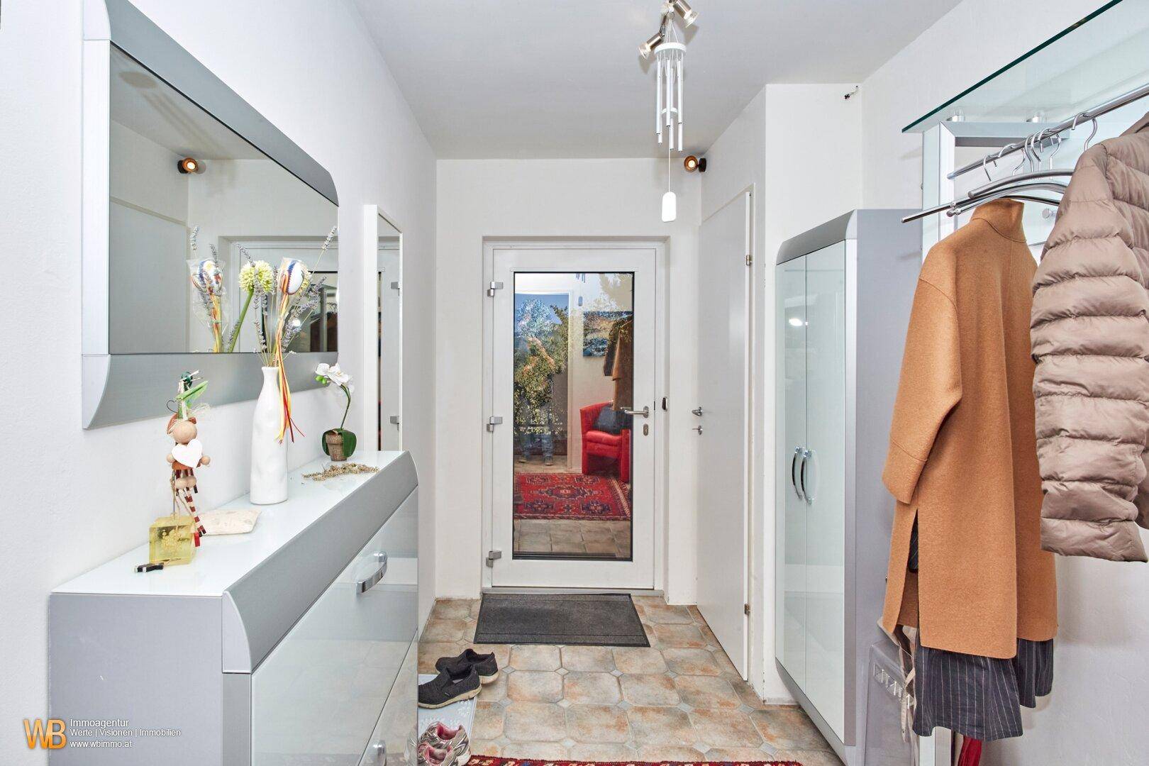 Heller Eingangsbereich mit Spiegel, Garderobe und Fliesenboden, der zum Verweilen einlädt.