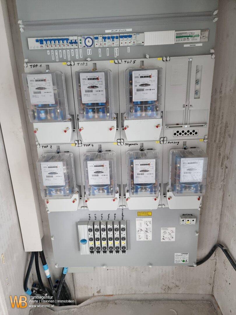 Elektrische Verteileranlage mit mehreren Stromzählern und Sicherungen, ordentlich installiert.