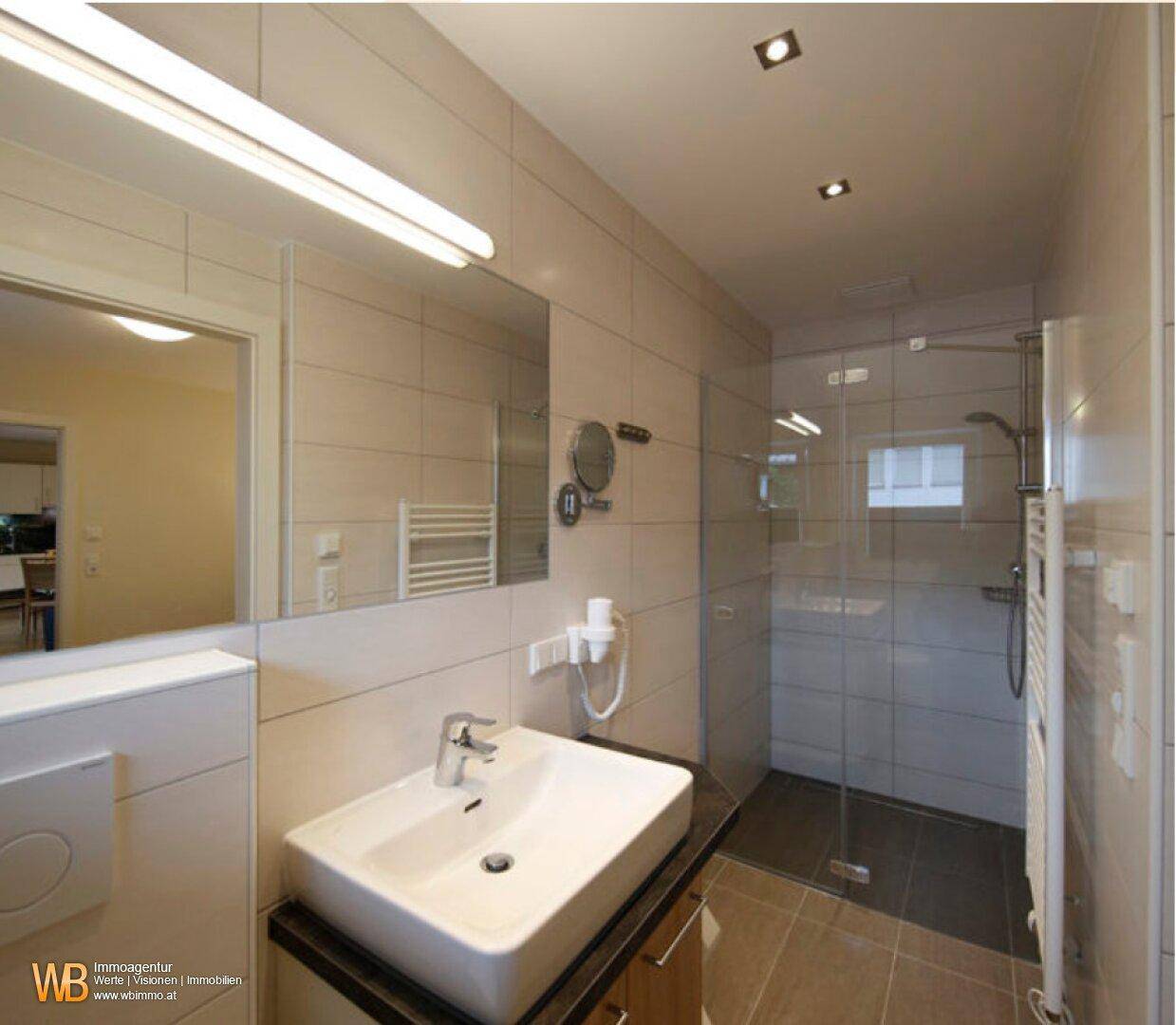 Modernes Badezimmer mit begehbarer Dusche, Waschbecken und beheiztem Handtuchhalter.