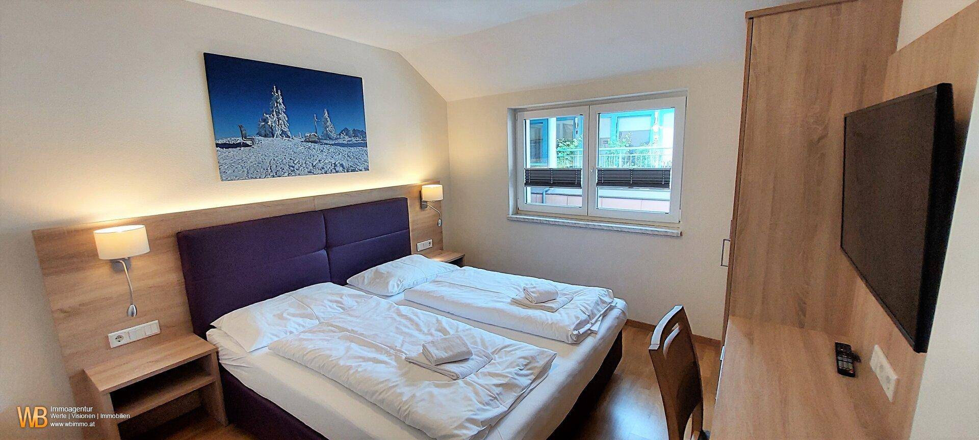 Gemütliches Schlafzimmer mit Doppelbett, Holzmöbeln und Fenster mit Blick ins Grüne.