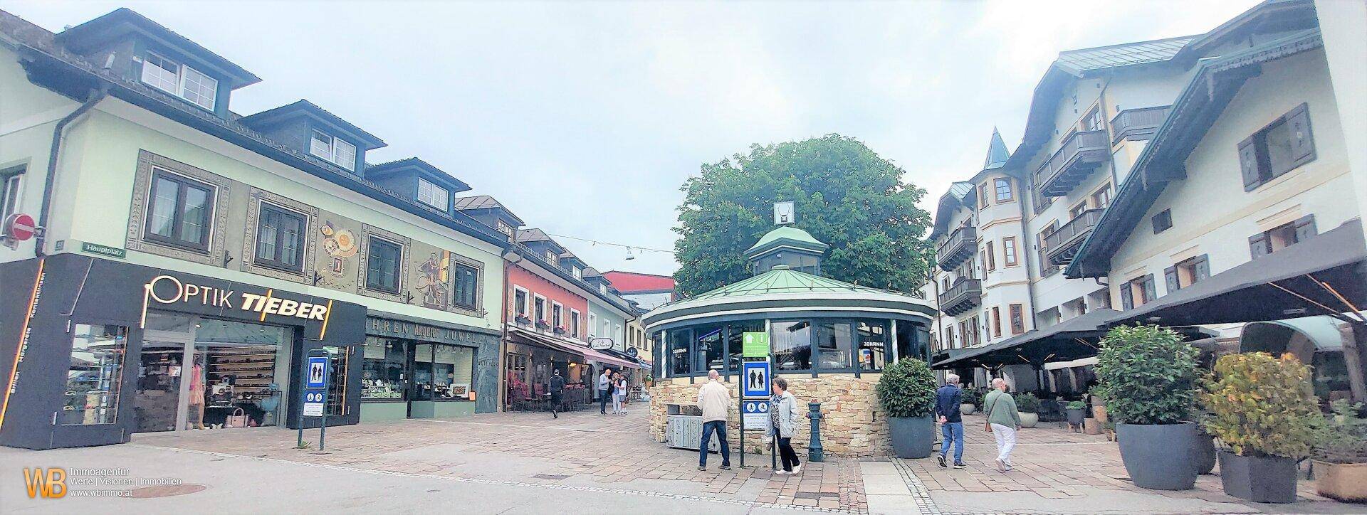 Belebter Stadtplatz mit Geschäften, Restaurants und traditioneller Architektur.