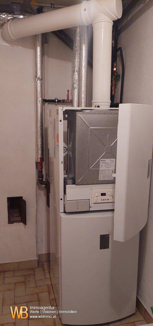 Heizungsanlage in einem Hauswirtschaftsraum mit sichtbaren Rohren.