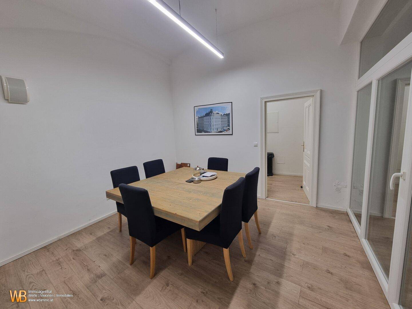 Konferenzraum mit einem großen Holztisch und schwarzen Stühlen, ideal für Team-Meetings.