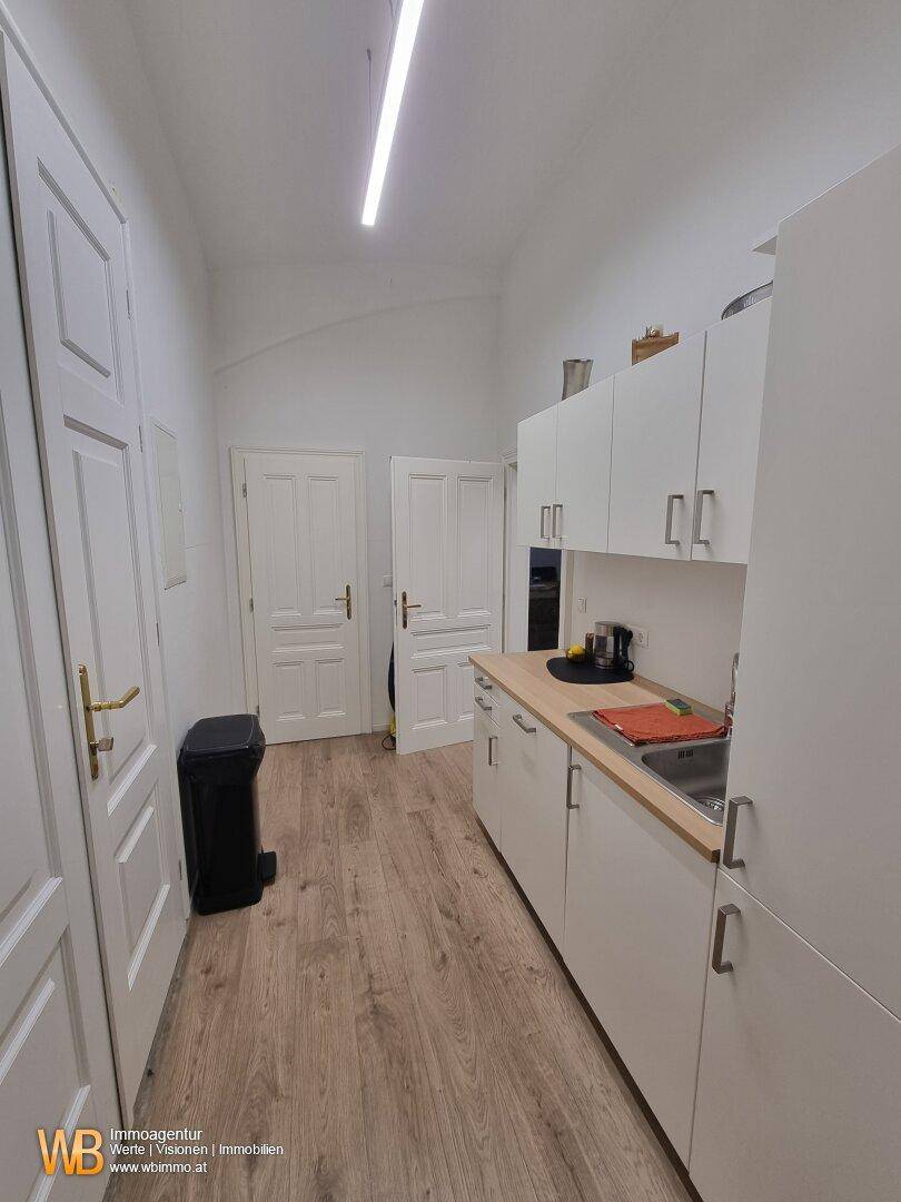 Kleine Küchenzeile mit weißen Schränken und Holz-Arbeitsplatte, praktisch und funktional.