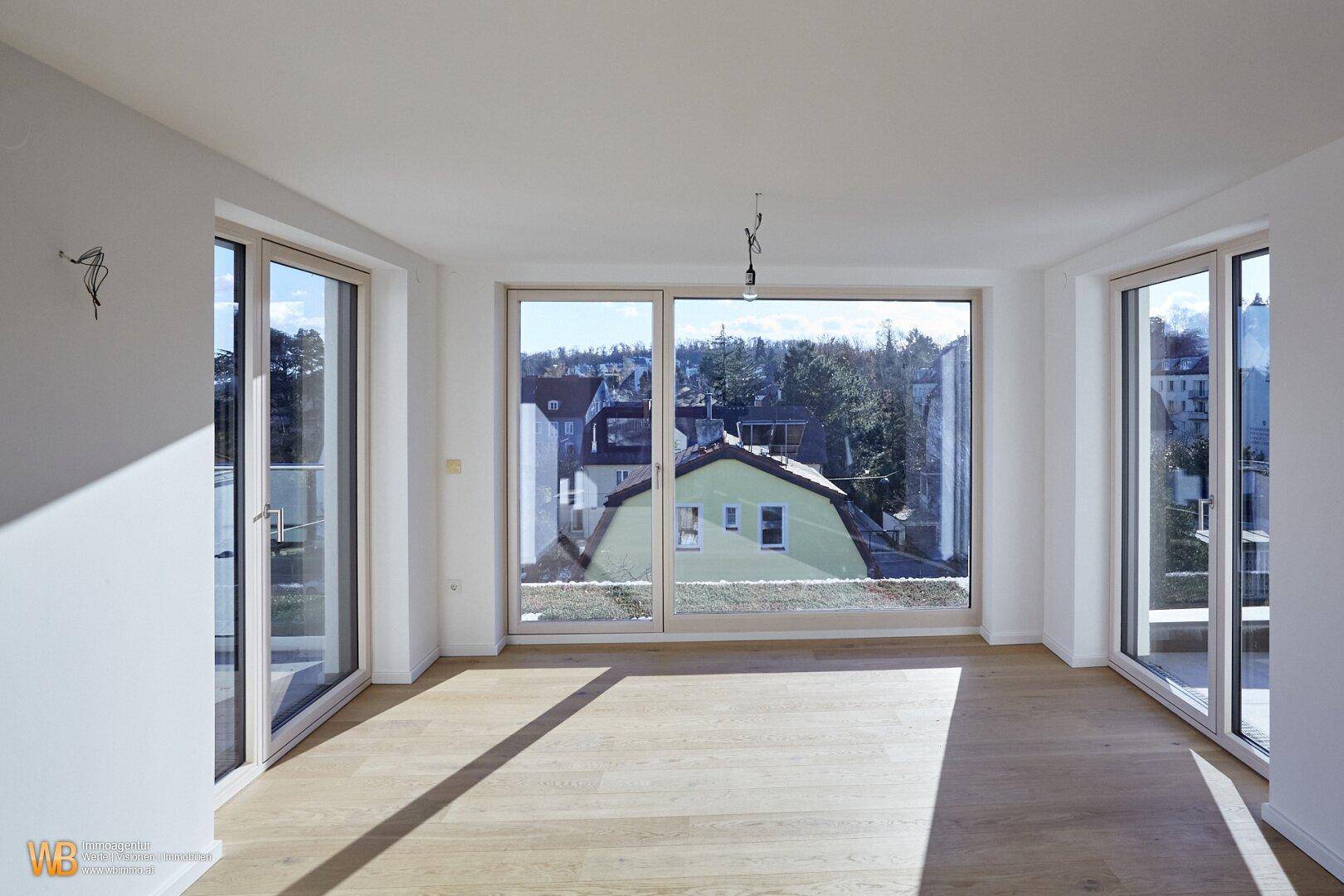 Große Fensterfronten im Wohnbereich bieten einen weiten Blick auf die umliegende Bebauung und Natur.