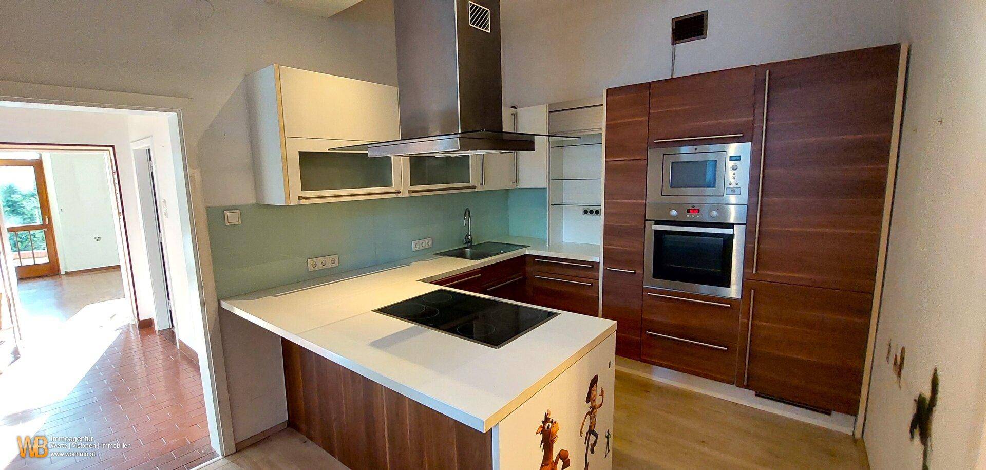 Moderne Küche mit Holzschränken, weißer Arbeitsplatte und integrierten Geräten, inklusive Induktionskochfeld.
