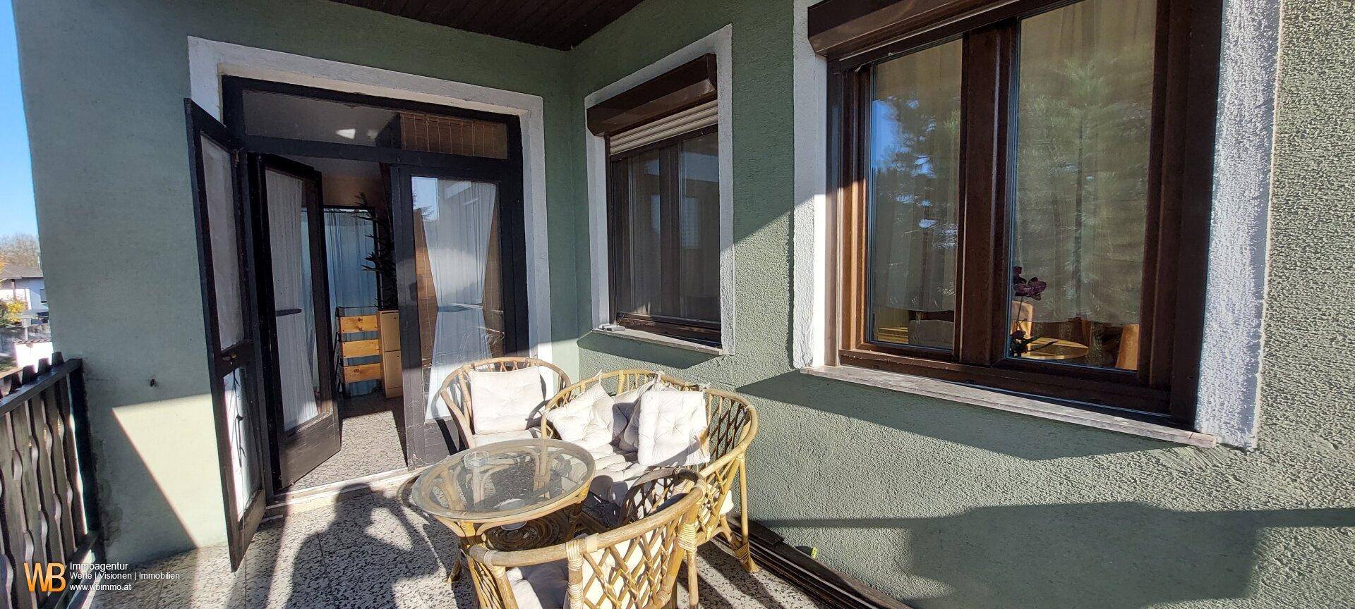 Balkon mit Sitzgelegenheiten und Zugang zum Innenbereich des Hauses.