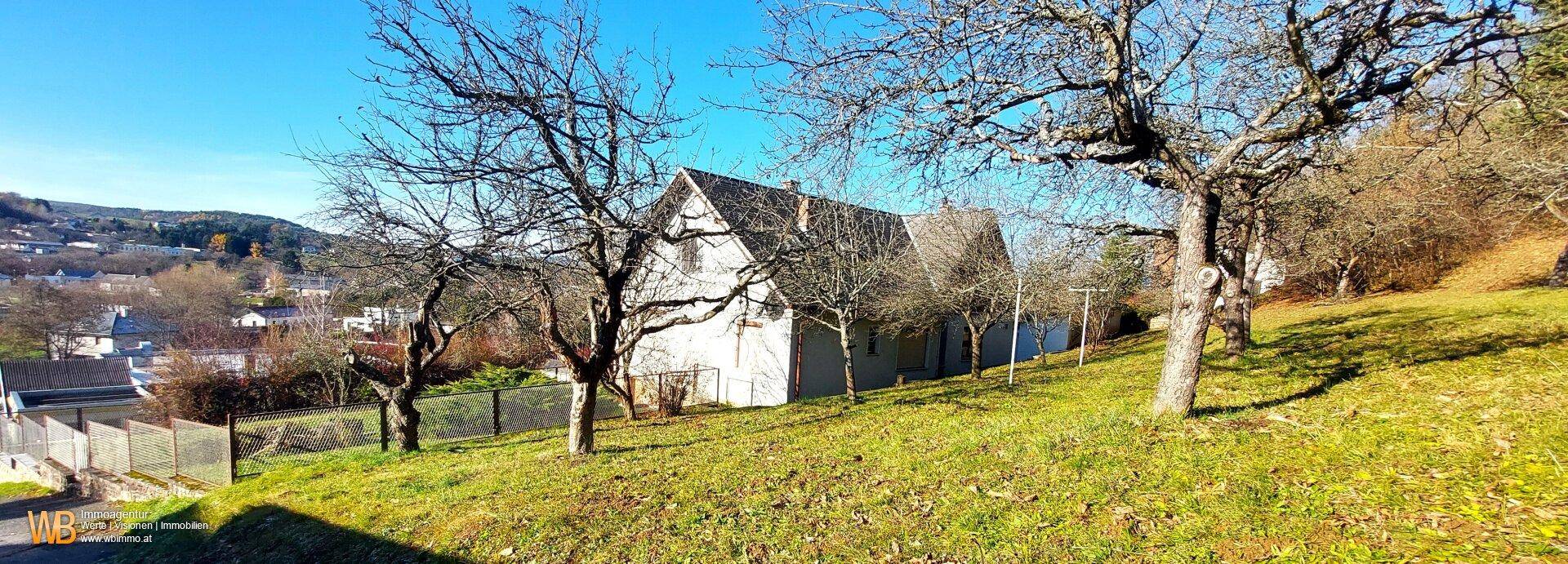 Das Haus liegt auf einem Hügel mit weitem Blick ins Grüne und umgeben von Bäumen.