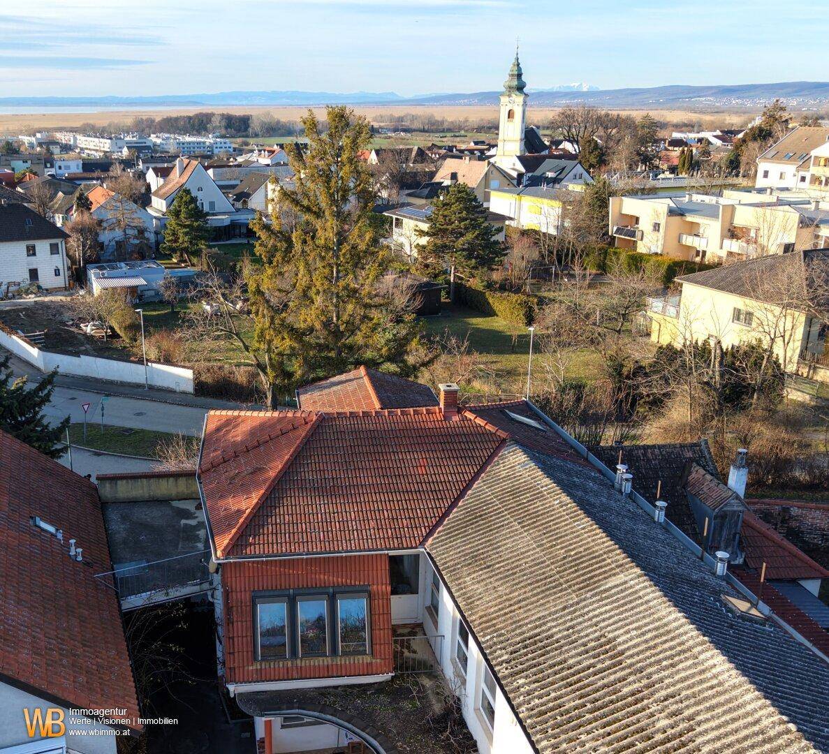 Luftaufnahme des Hauses mit rotem Ziegeldach und Blick auf die umliegende Ortschaft und Landschaft.