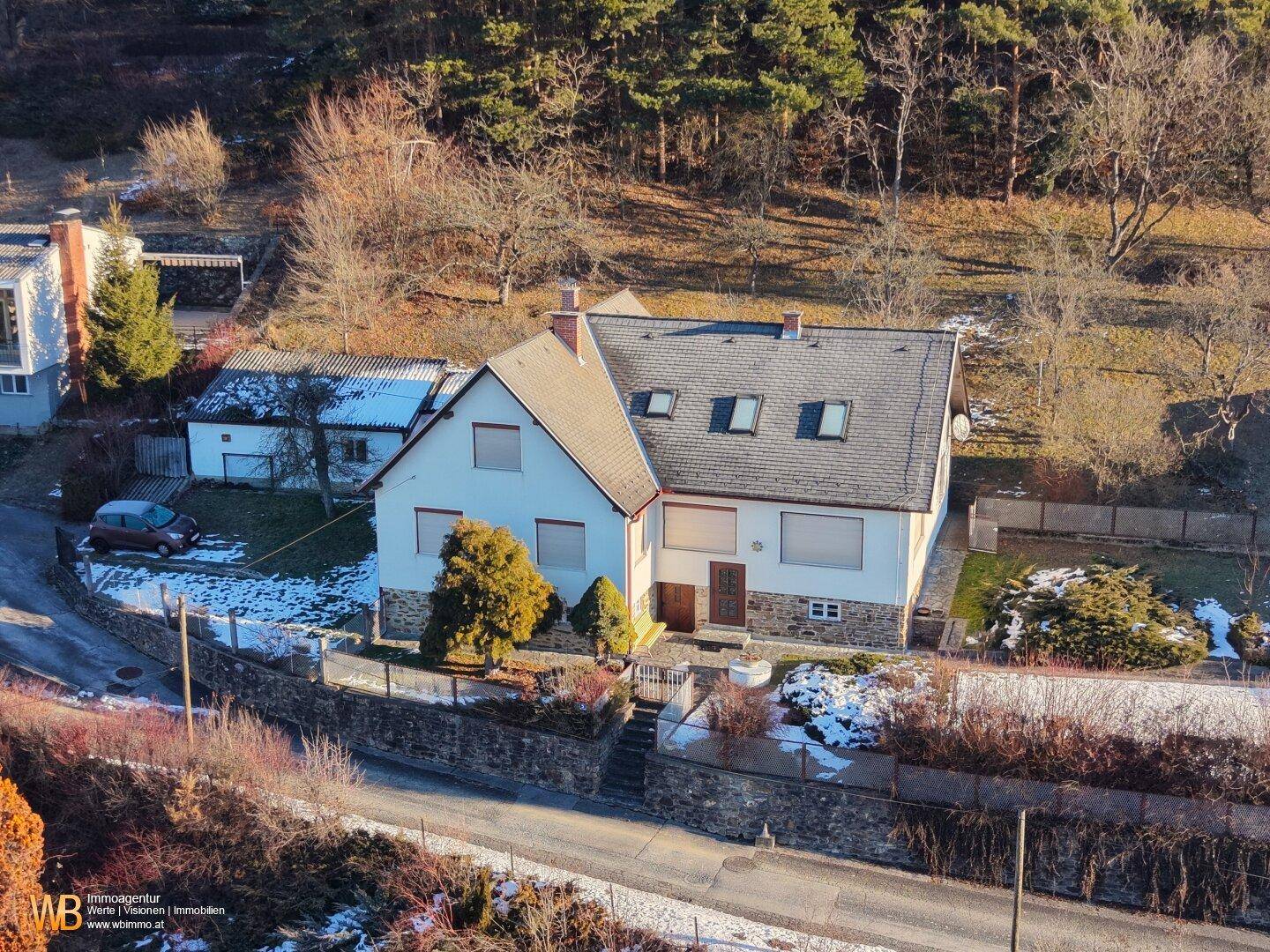 Einfamilienhaus mit großem Grundstück und Blick auf die bewaldete Hügellandschaft.