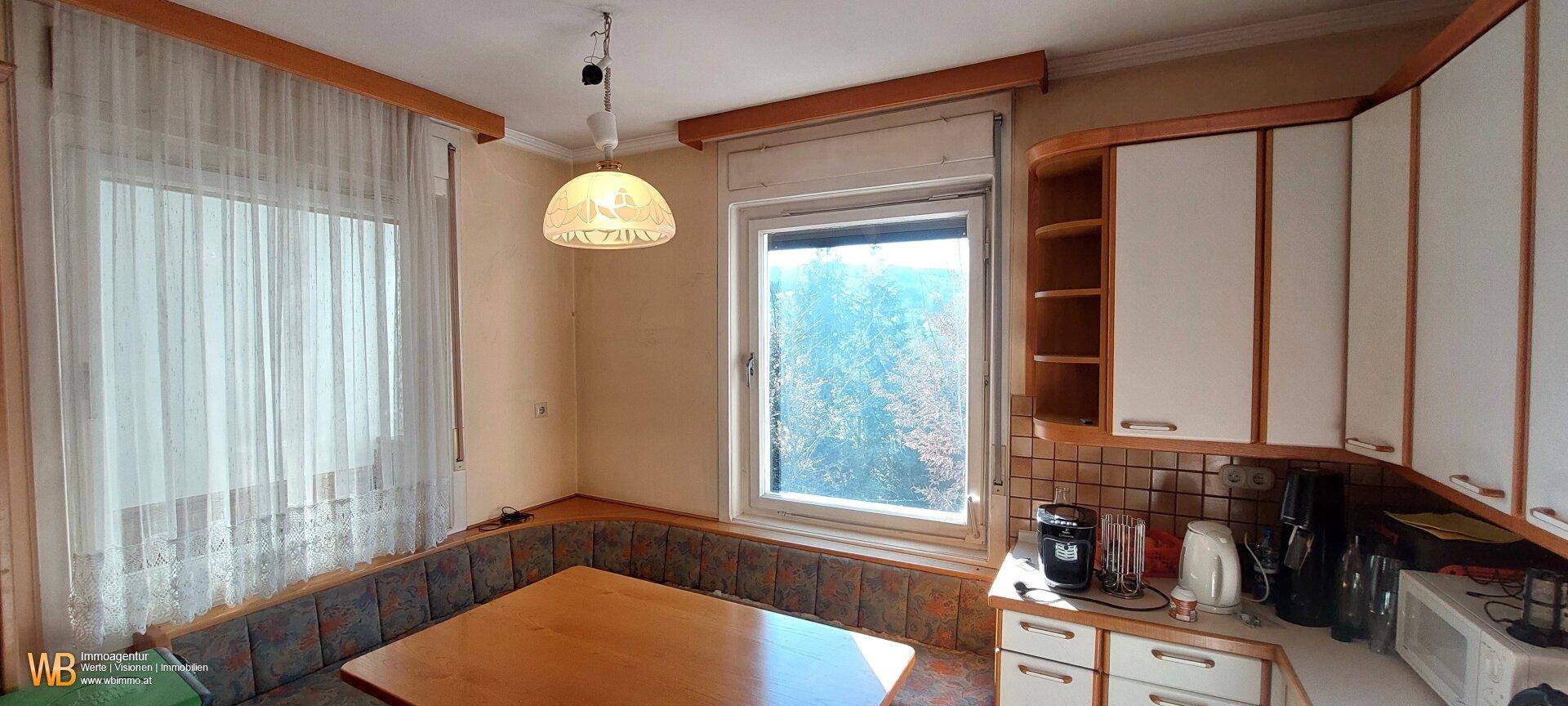 Gemütliche Wohnküche mit Einbaumöbeln, Essbereich und Fenster mit Blick ins Grüne.