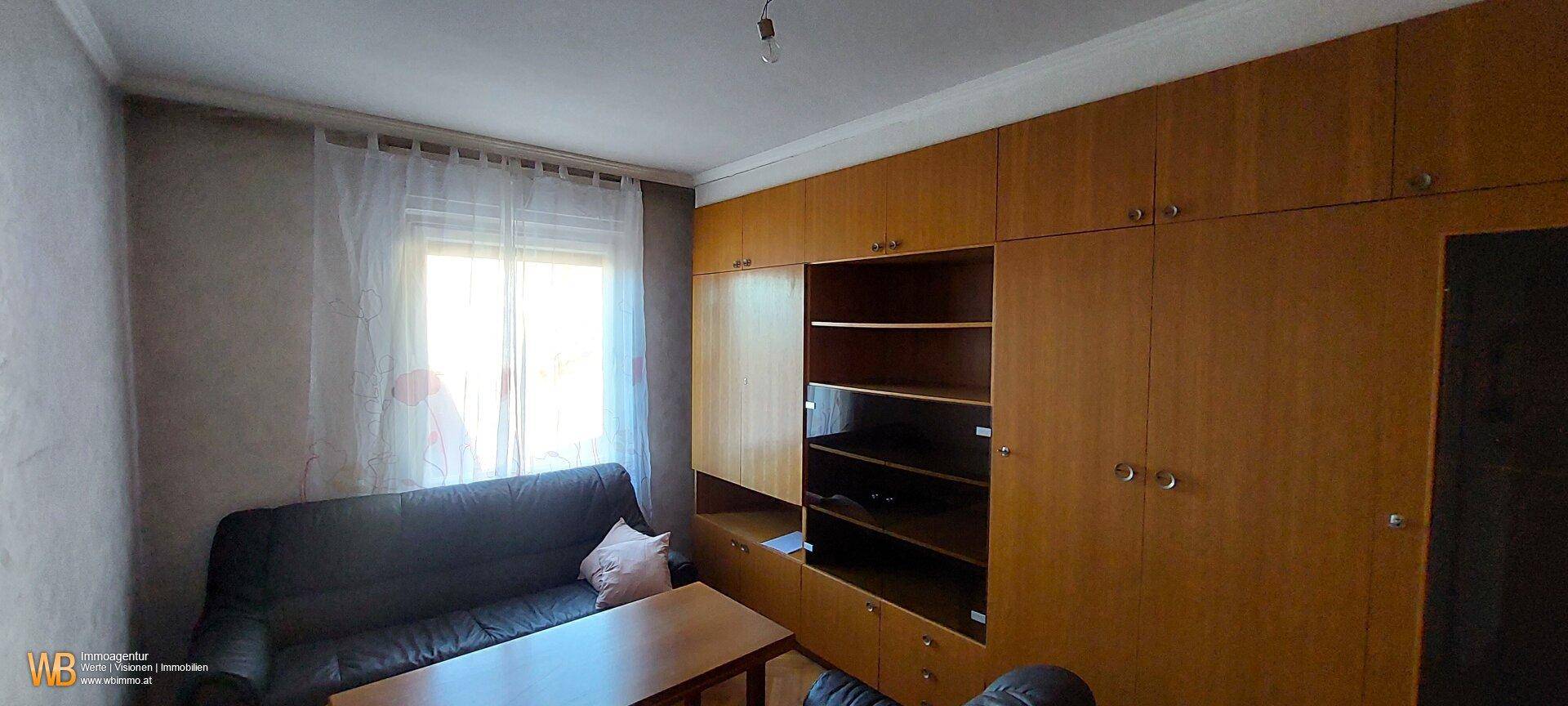 Zimmer mit großen Einbauschränken aus Holz und einem Fenster, das viel Tageslicht hereinlässt.