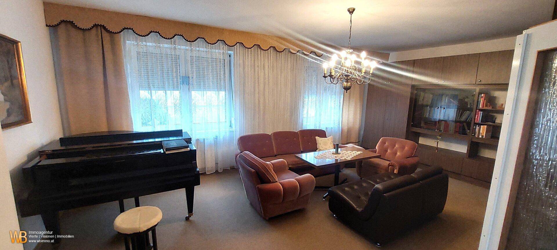 Geräumiges Wohnzimmer mit Klavier, bequemen Sofas und großen Fenstern für viel Licht.