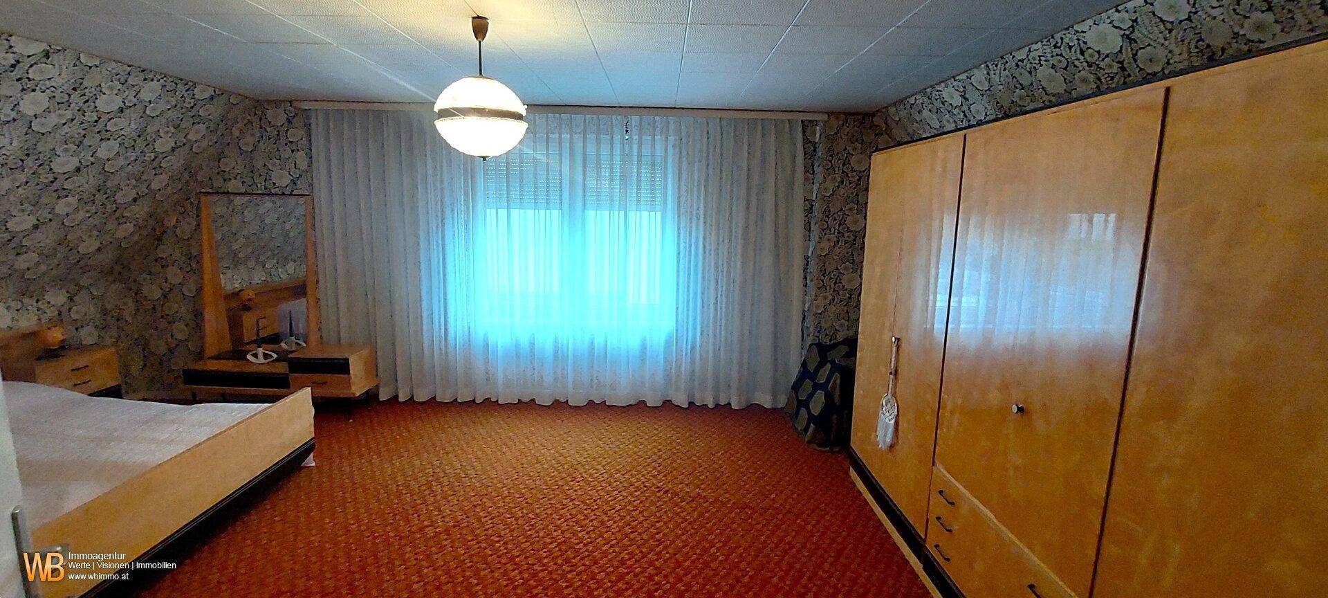 Schlafzimmer im Retro-Stil mit Doppelbett, Kleiderschrank und gemusterter Tapete.