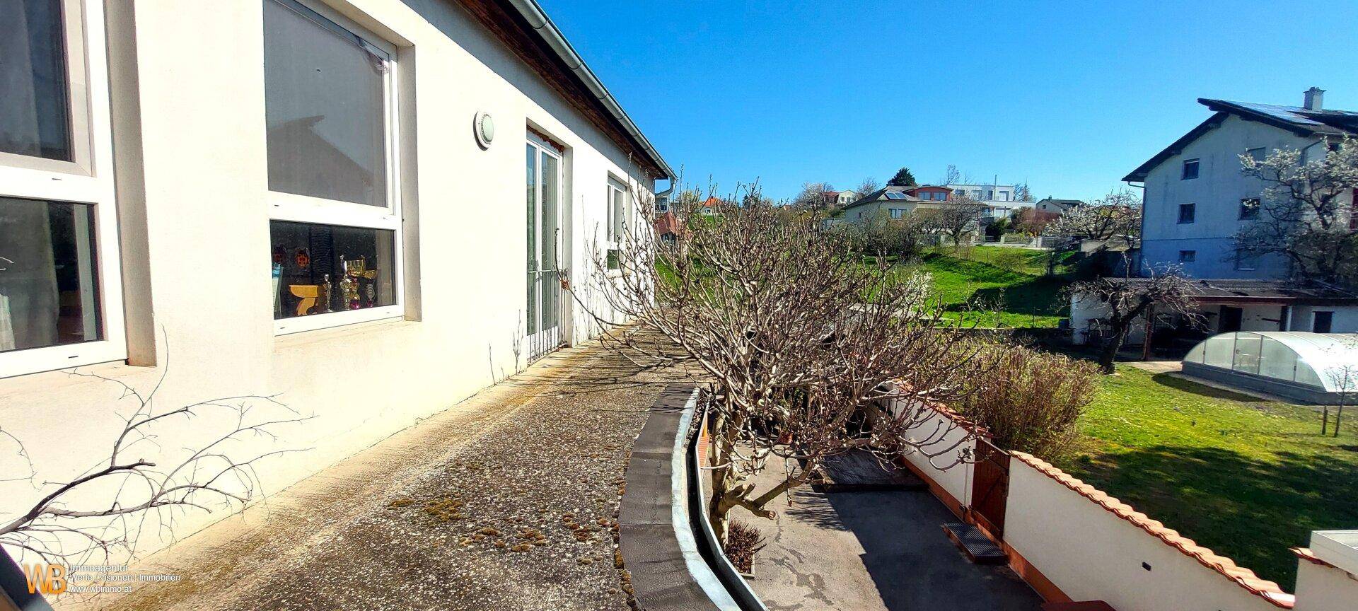 Seitlicher Zugang zum Gartenbereich mit Gewächshaus und Blick ins Grüne, ruhig gelegen.