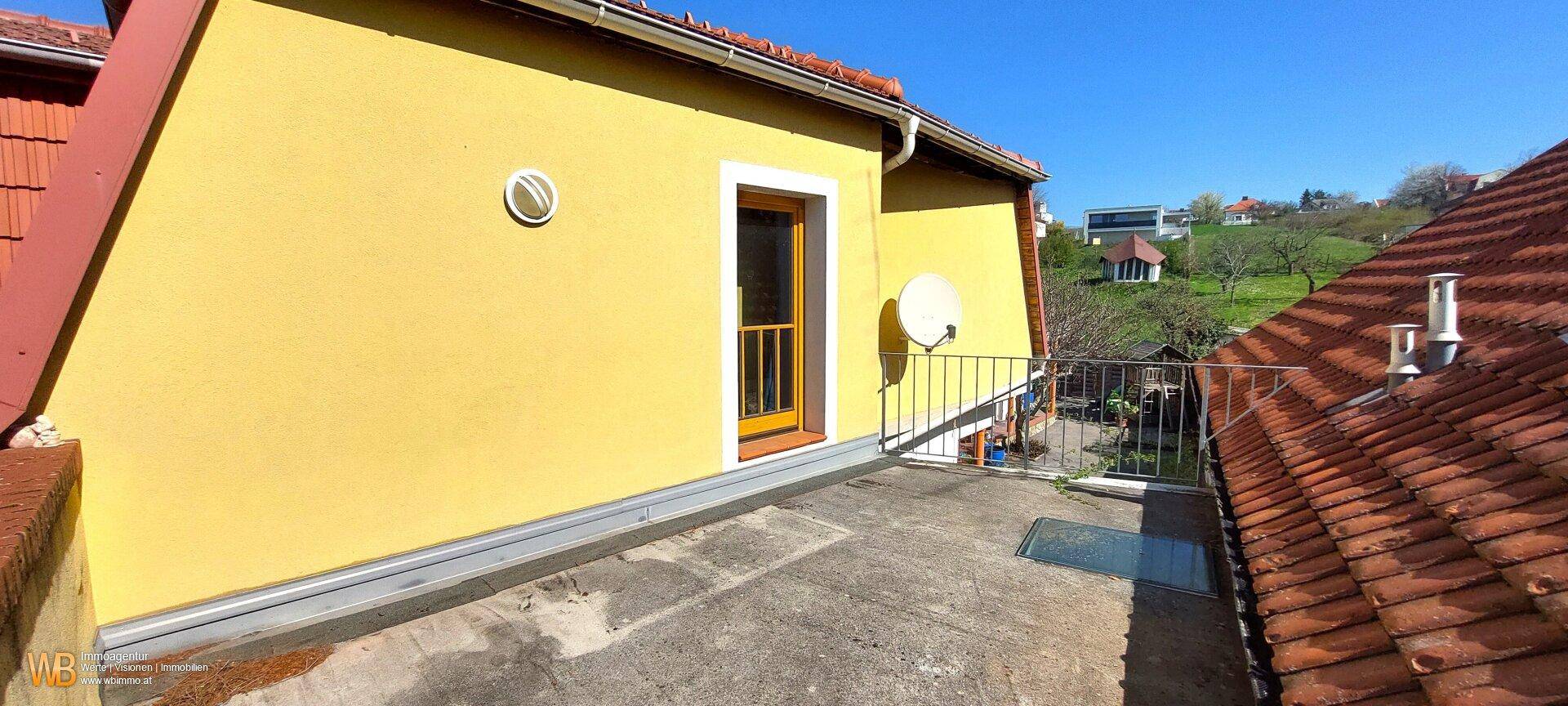 Kleine Dachterrasse mit Metallgeländer und Blick ins Grüne, ideal für sonnige Stunden.