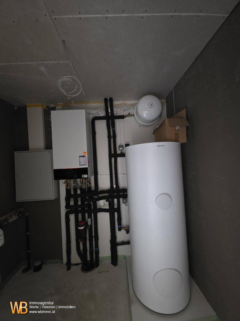 Technikraum mit moderner Heizungsanlage und Warmwasserspeicher im Neubau.