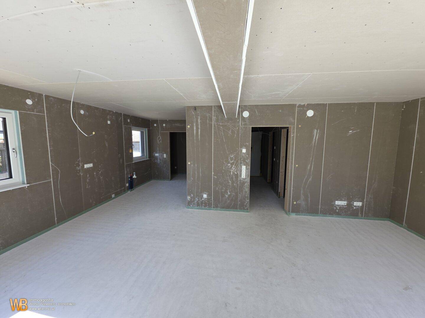 Großer Raum im Rohbau mit mehreren Zugängen und Fenstern, ideal für individuelle Gestaltung.