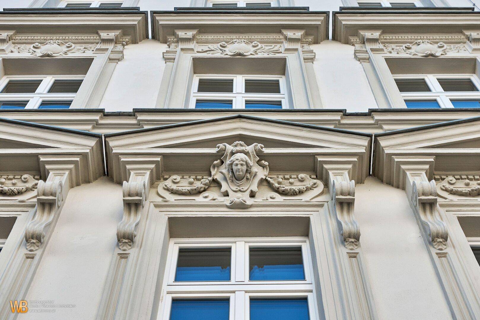Detailansicht der aufwendig verzierten Fassade eines historischen Gebäudes mit Stuckelementen.