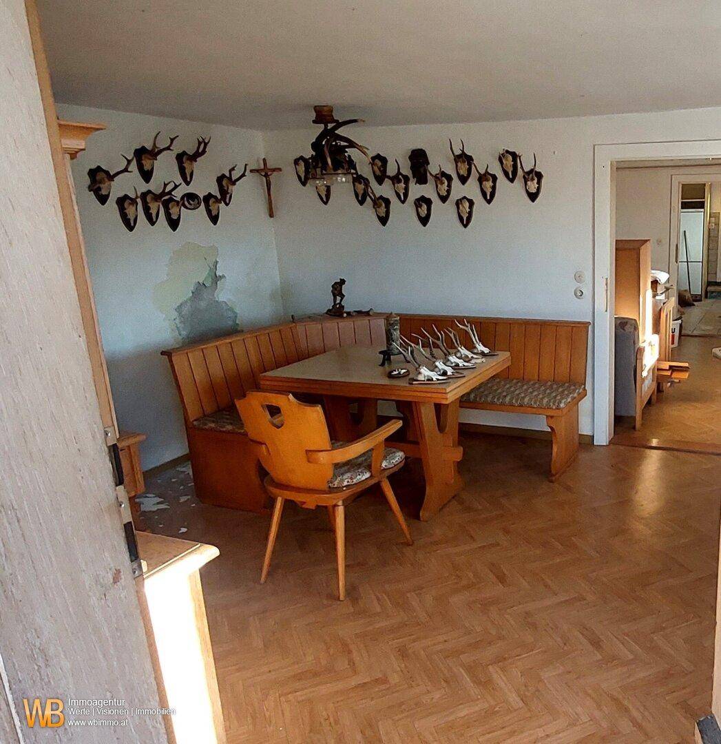 Rustikaler Essbereich mit Eckbank, Holztisch und traditioneller Jagdtrophäen-Dekoration an der Wand.