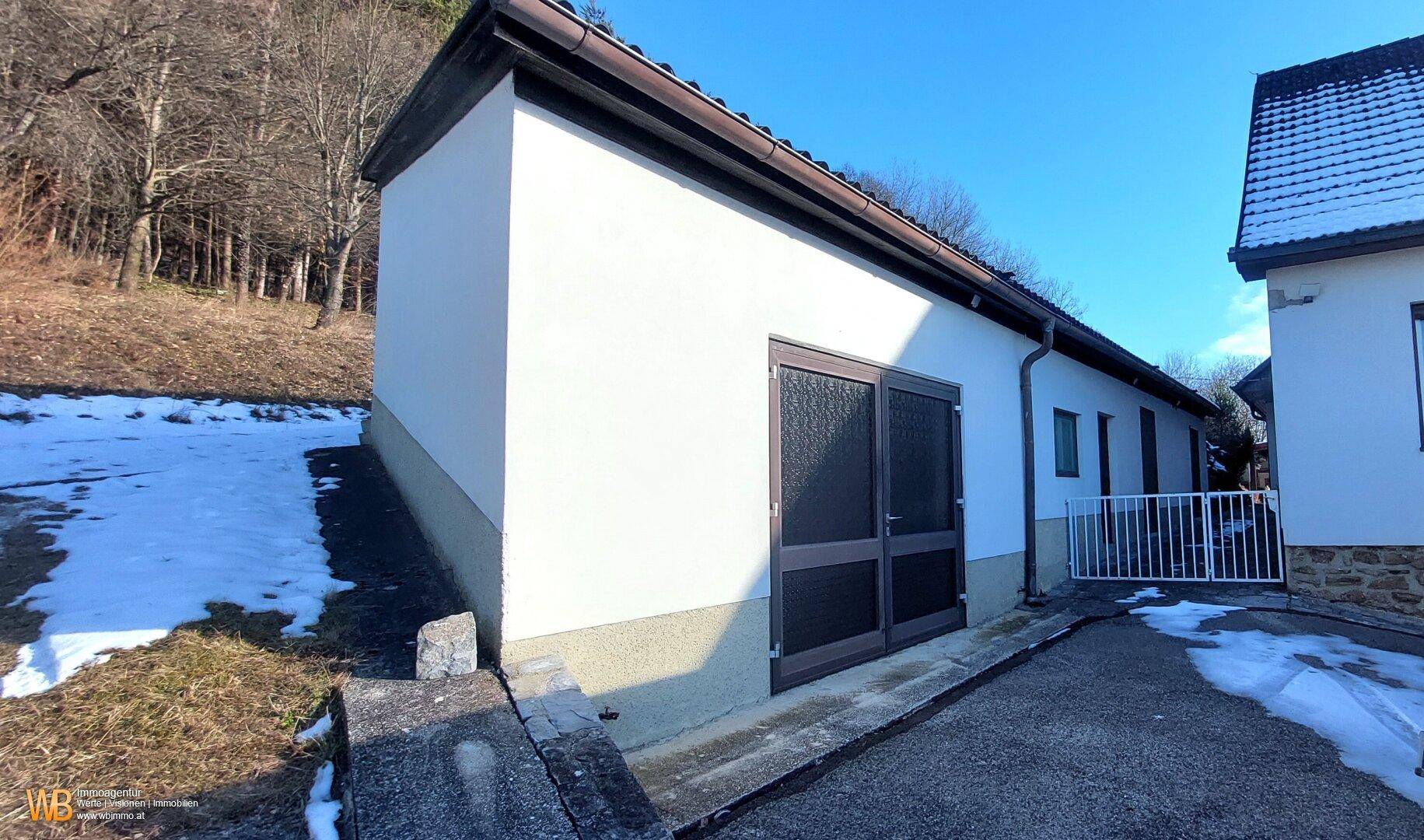 Seitenansicht einer Garage oder eines Nebengebäudes mit zwei Türen und schneebedecktem Boden.