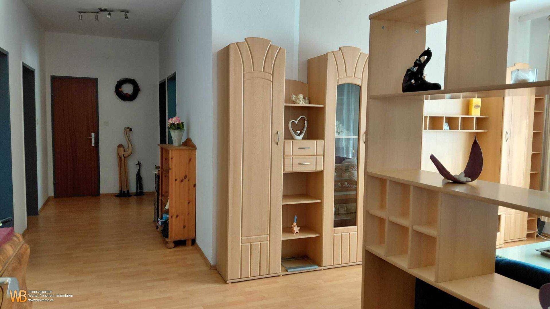 Heller Eingangsbereich mit Laminatboden, Holzmöbeln und dekorativen Akzenten.
