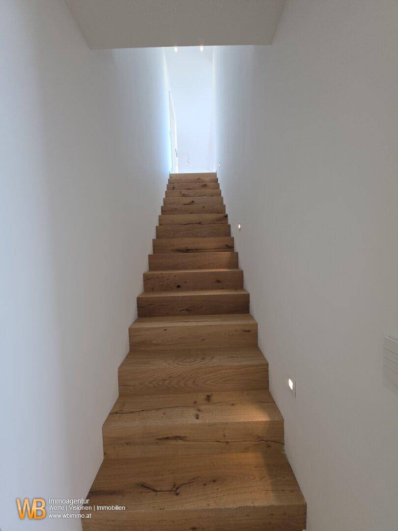 Moderne Holztreppe mit indirekter Beleuchtung, die elegant in die obere Etage führt.