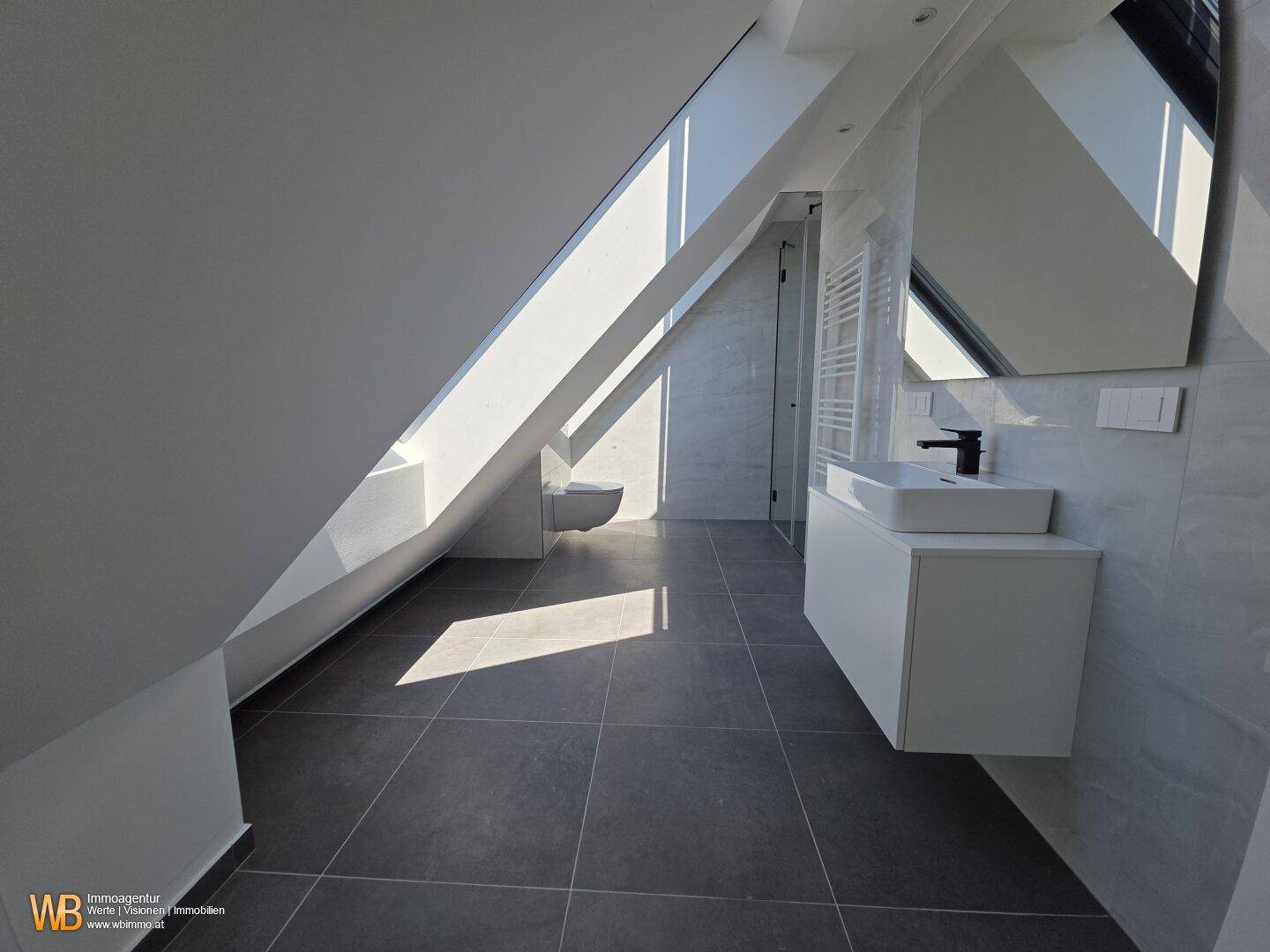 Geräumiges Badezimmer im Dachgeschoss mit Schrägen, modernem Waschtisch und viel Tageslicht.