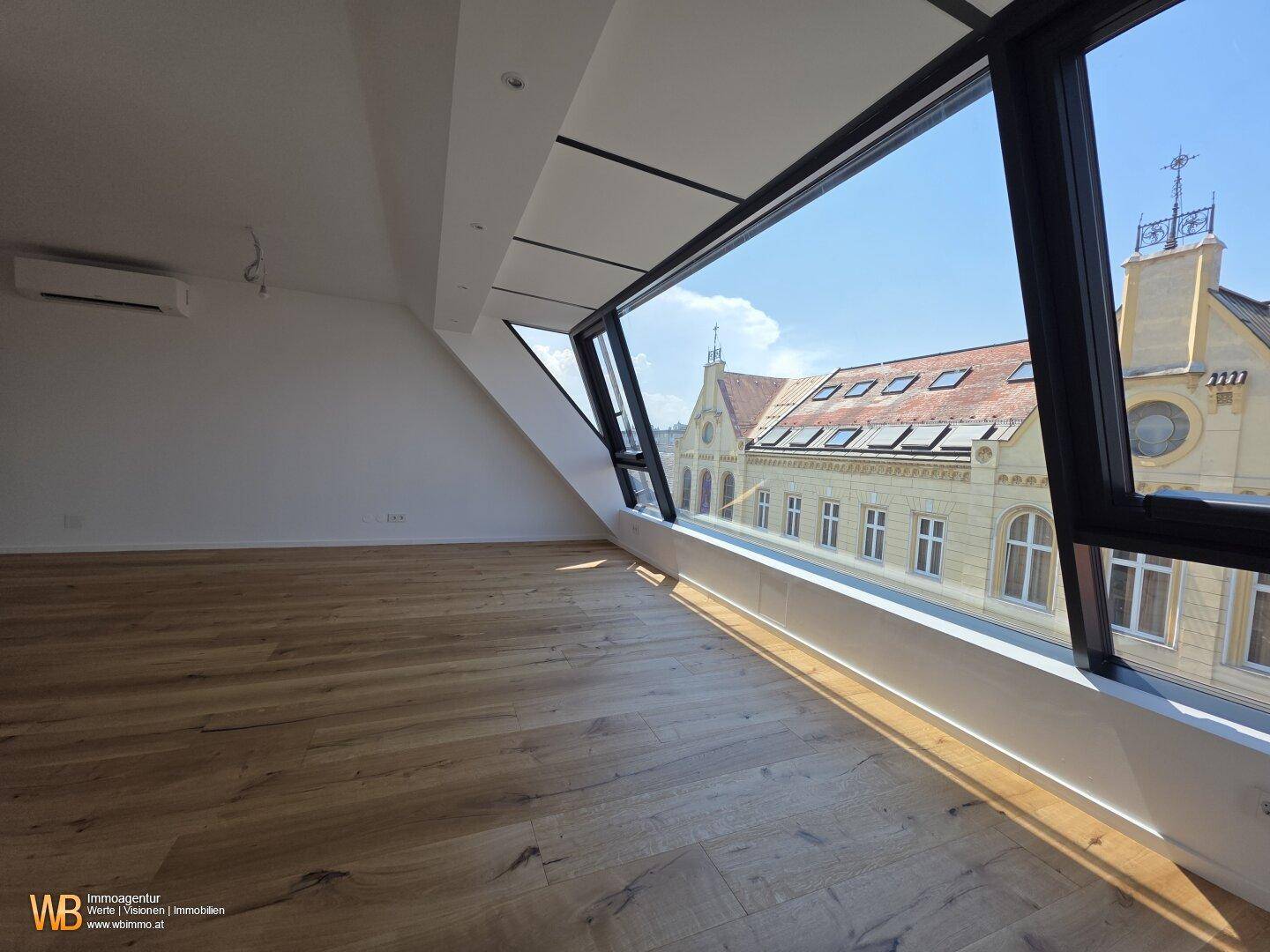 Heller Wohnraum mit Holzboden und großer Fensterfront, die einen weiten Stadtblick bietet.