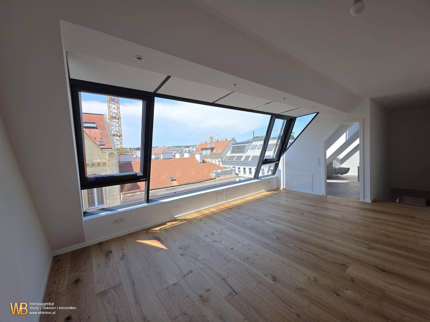 Geräumiger Wohnbereich mit Holzboden und großer Fensterfront, die einen weiten Stadtblick bietet.