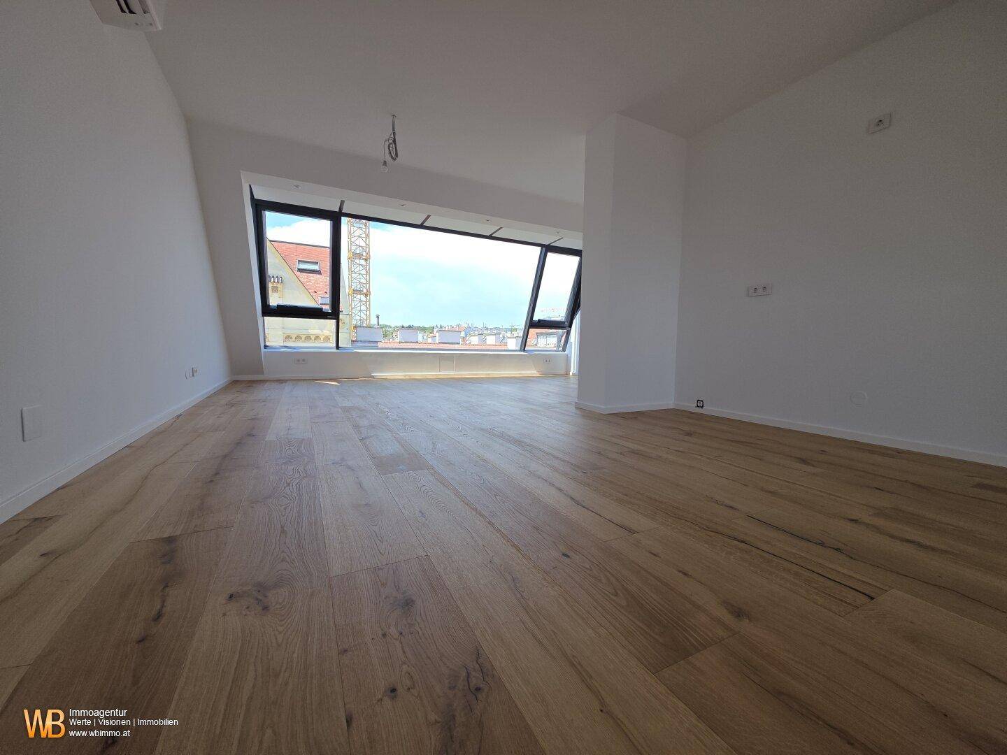 Heller Wohnraum mit Holzboden und großer Fensterfront, die einen weiten Stadtblick bietet.
