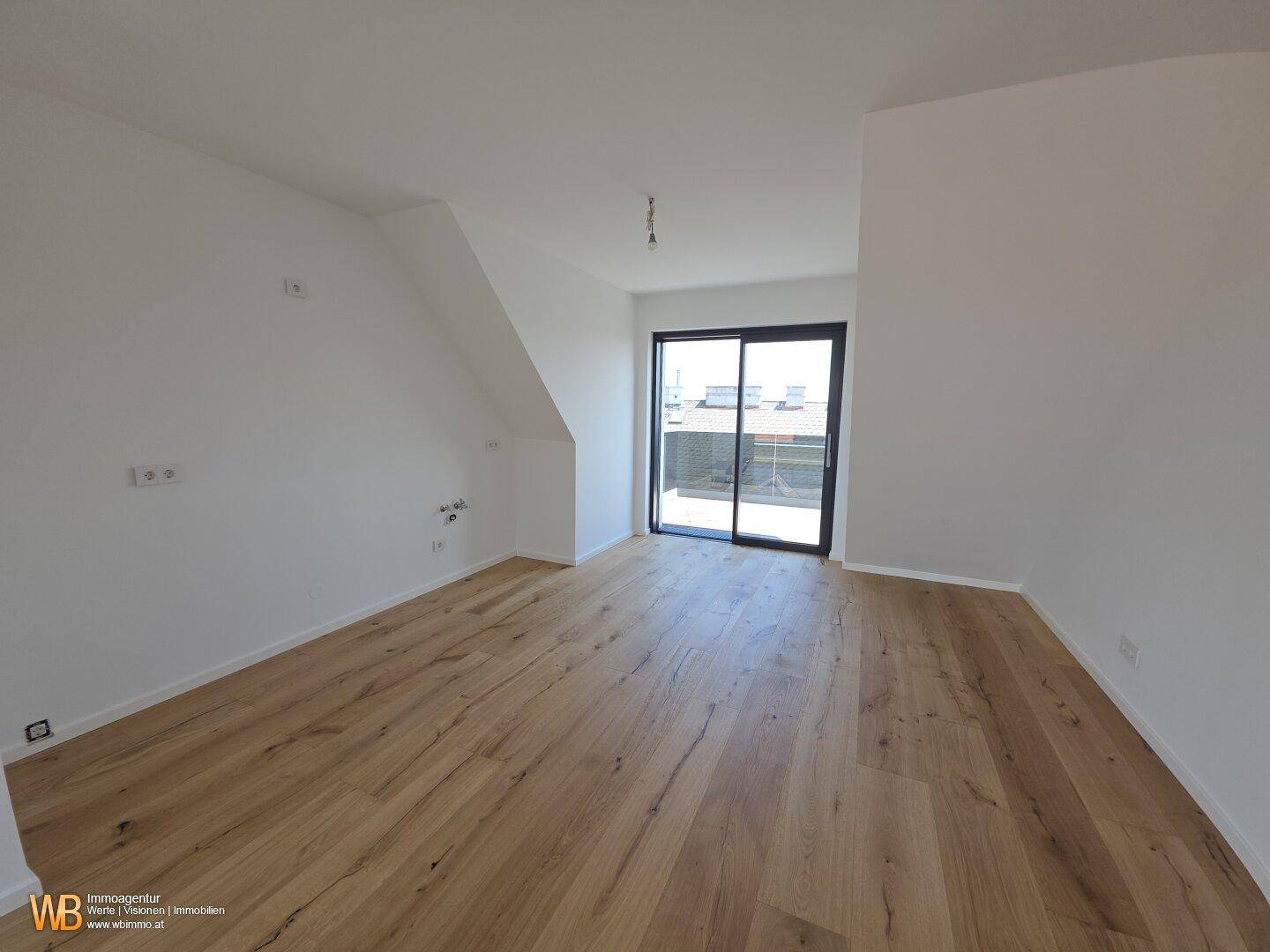 Heller Raum mit Holzboden und Zugang zu einer Terrasse durch eine Glasschiebetür.