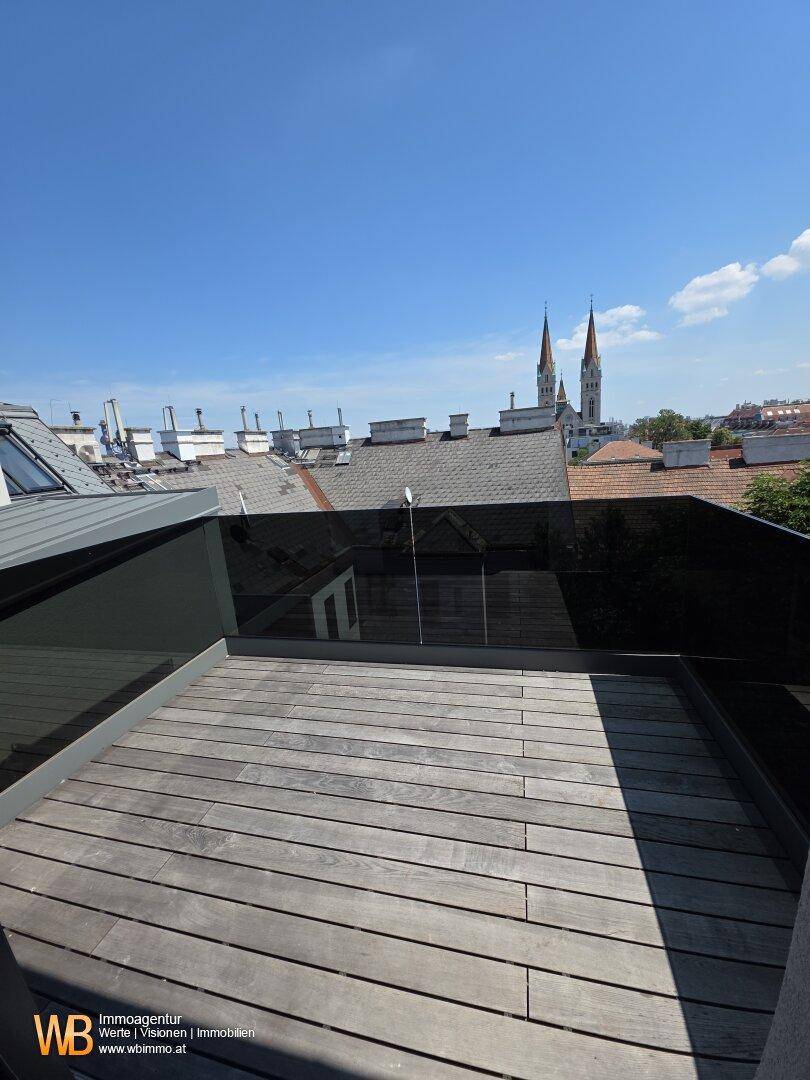 Dachterrasse mit Holzdielenboden und Glasbrüstung, bietet einen weiten Stadtblick.