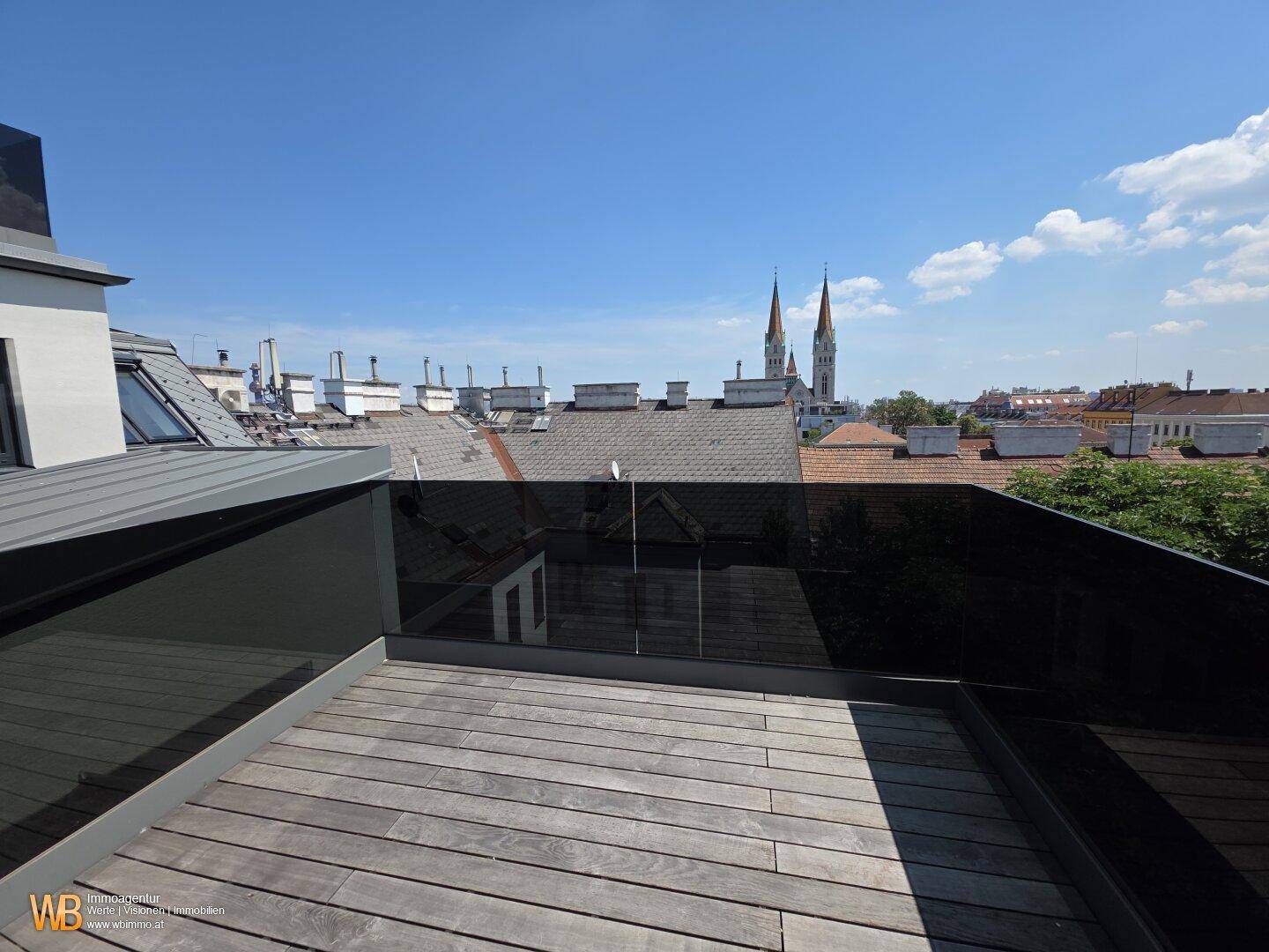Geräumige Dachterrasse mit Holzdielen und Glasgeländer, ideal für Entspannung im Freien.