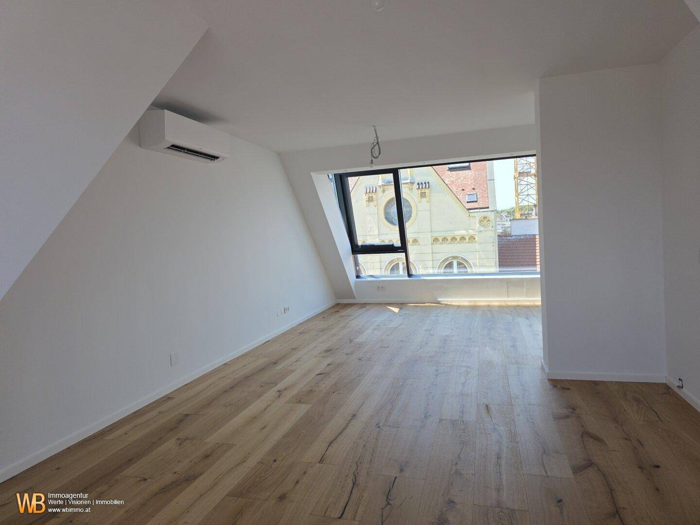 Heller Wohnraum mit Holzboden, Klimaanlage und großer Fensterfront mit Stadtblick.