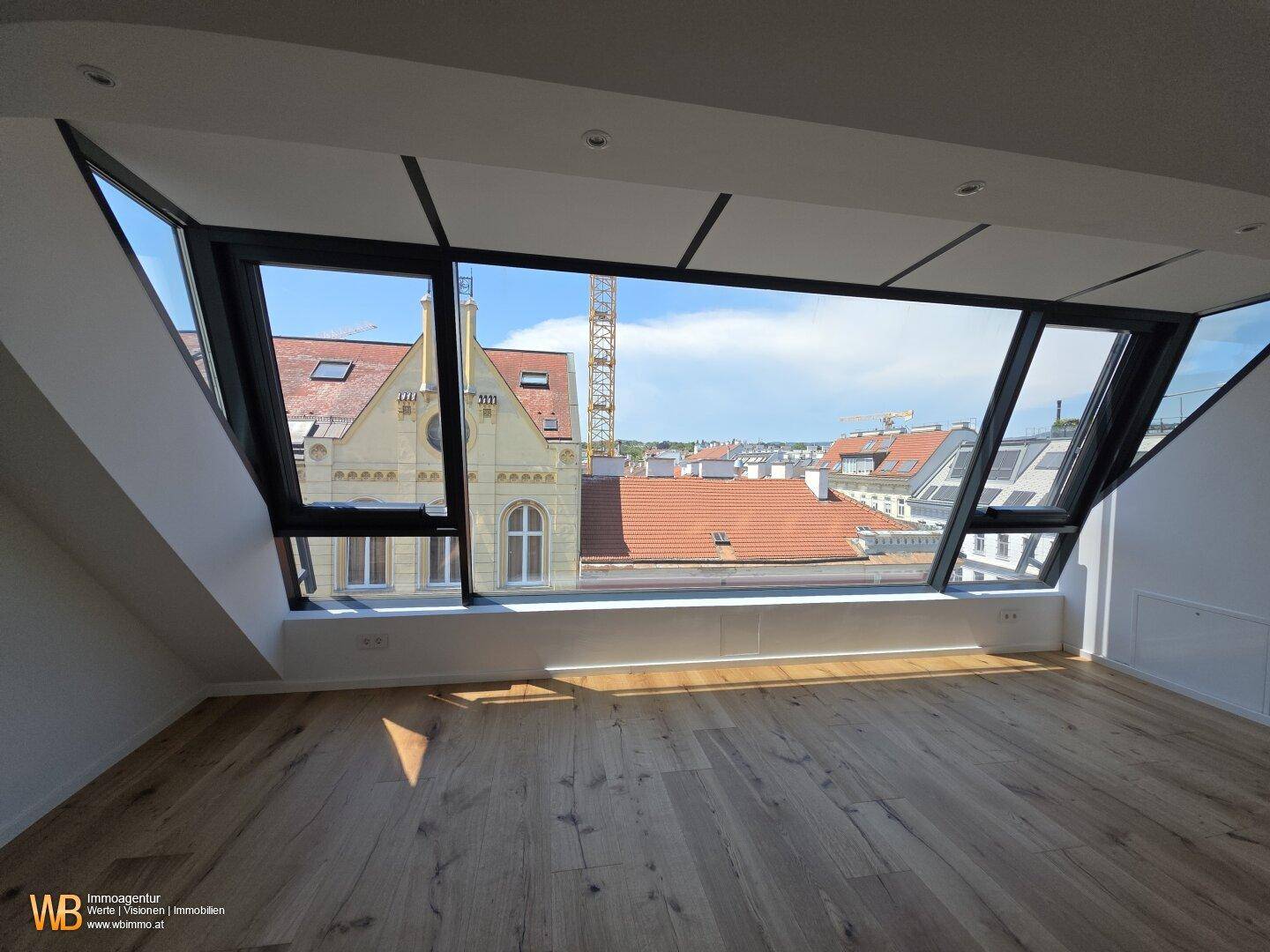Heller Wohnraum mit Holzboden und großer Fensterfront, die einen weiten Stadtblick bietet.