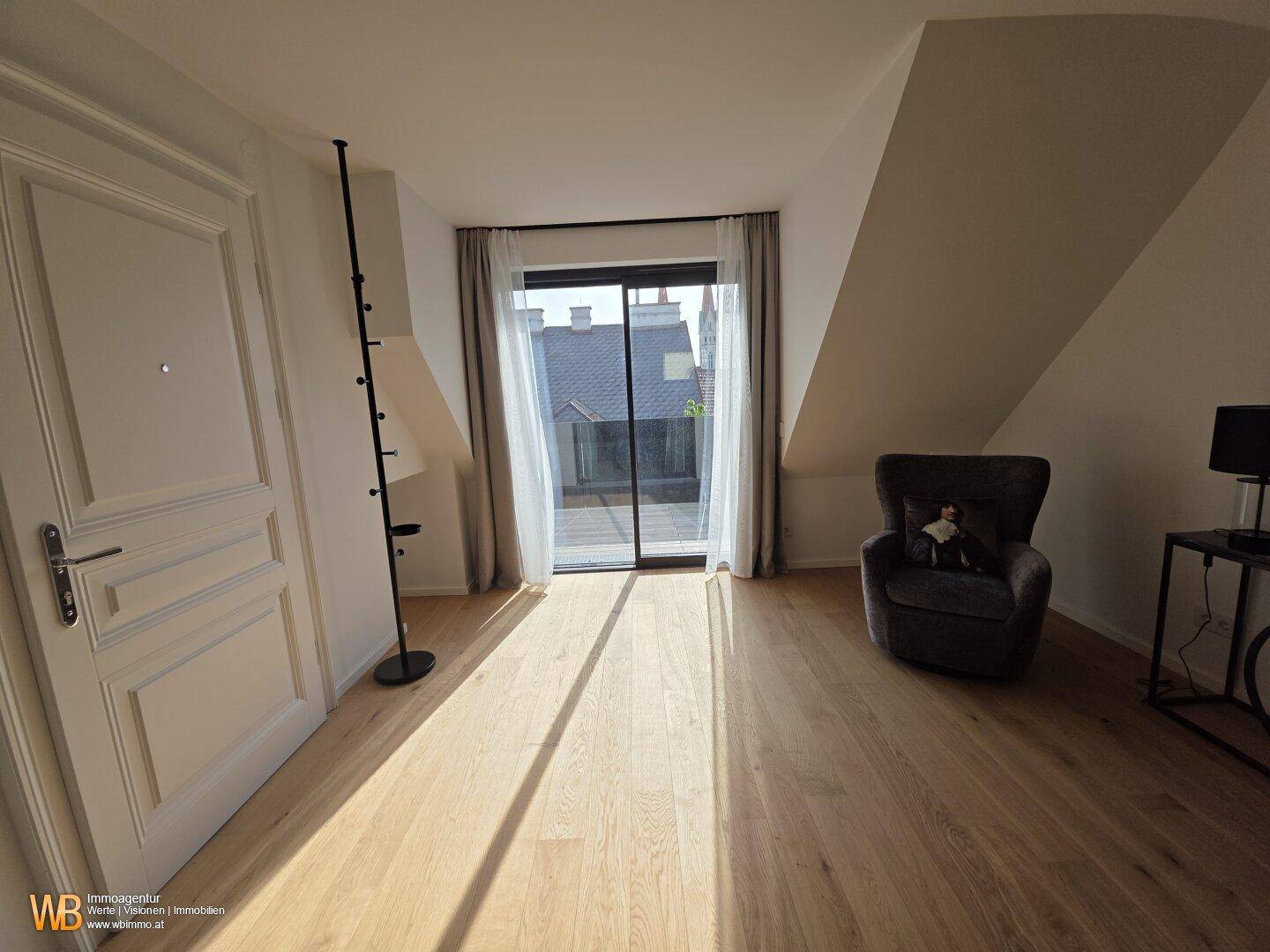 Helles Zimmer mit Holzboden, Dachschrägen und direktem Zugang zu einer Terrasse oder Balkon.