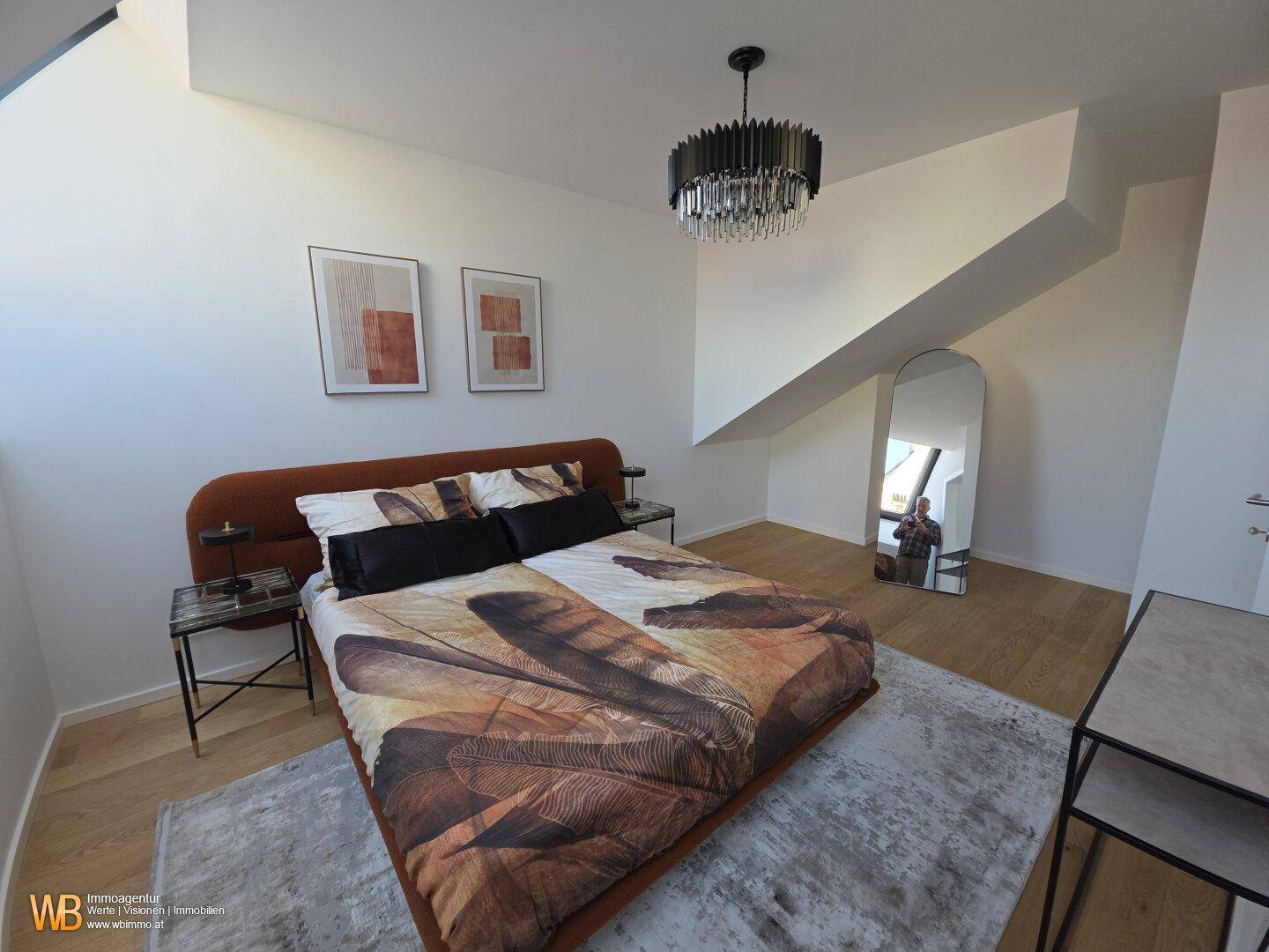 Geräumiges Schlafzimmer mit Holzboden, Dachschrägen und einem großen Spiegel, hell durch Dachfenster.