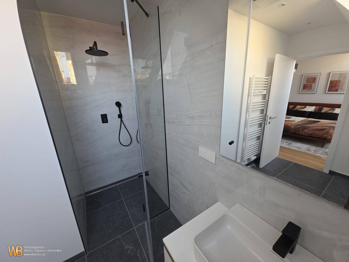 Begehbare Dusche im modernen Badezimmer mit Regenduschkopf und eleganten grauen Wandfliesen.