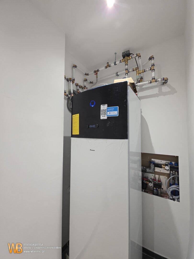 Technikraum mit Wärmepumpensystem und sichtbaren Rohrleitungen für die Gebäudetechnik.