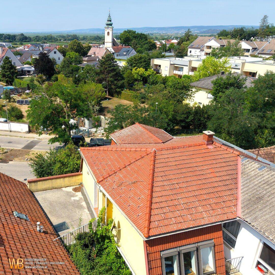 Luftaufnahme des Hauses mit Blick auf die umliegende Wohngegend und Kirchturm in der Ferne.
