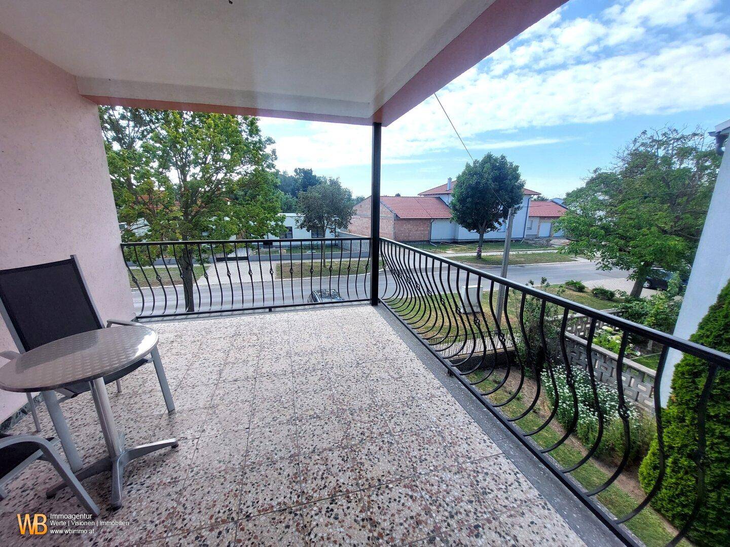 Möblierter Balkon mit schmiedeeisernem Geländer und Blick auf die Straße und die Umgebung.