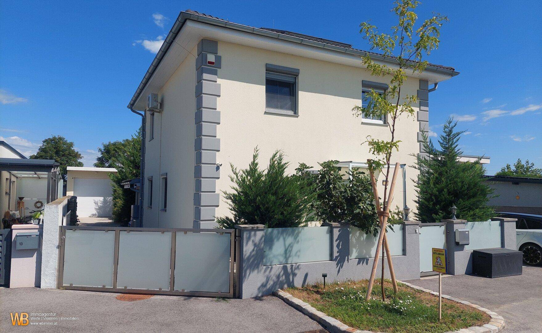 Vorderansicht des modernen Einfamilienhauses mit gepflegtem Vorgarten und Einfahrtstor.