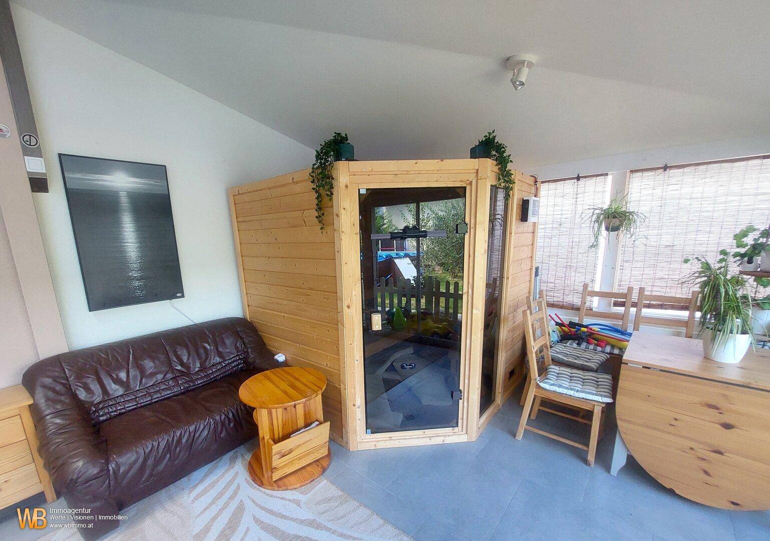 Entspannungsbereich mit privater Sauna, bequemer Ledercouch und viel Tageslicht durch große Fenster.