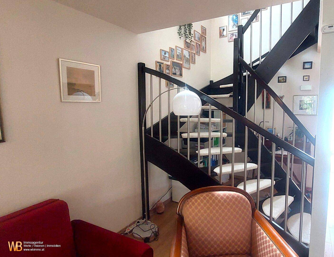 Elegante Holztreppe mit Metallgeländer und einer Fotogalerie an der Wand, die die Etagen verbindet.