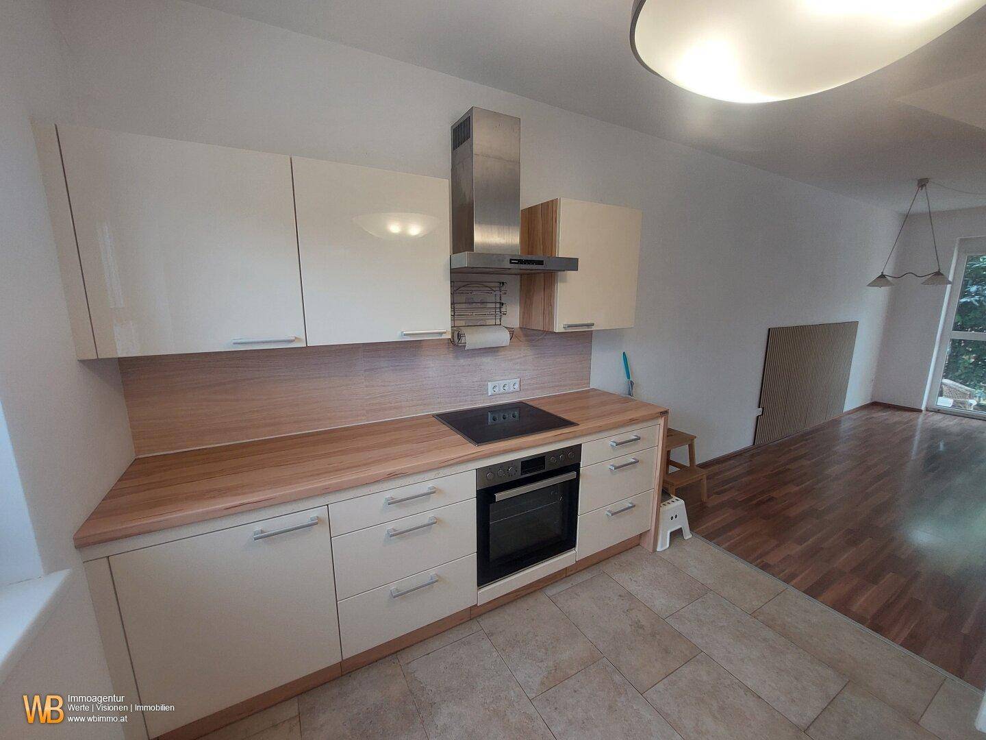 Moderne Küche mit Kochfeld, Backofen, Dunstabzugshaube und hellen Schränken.