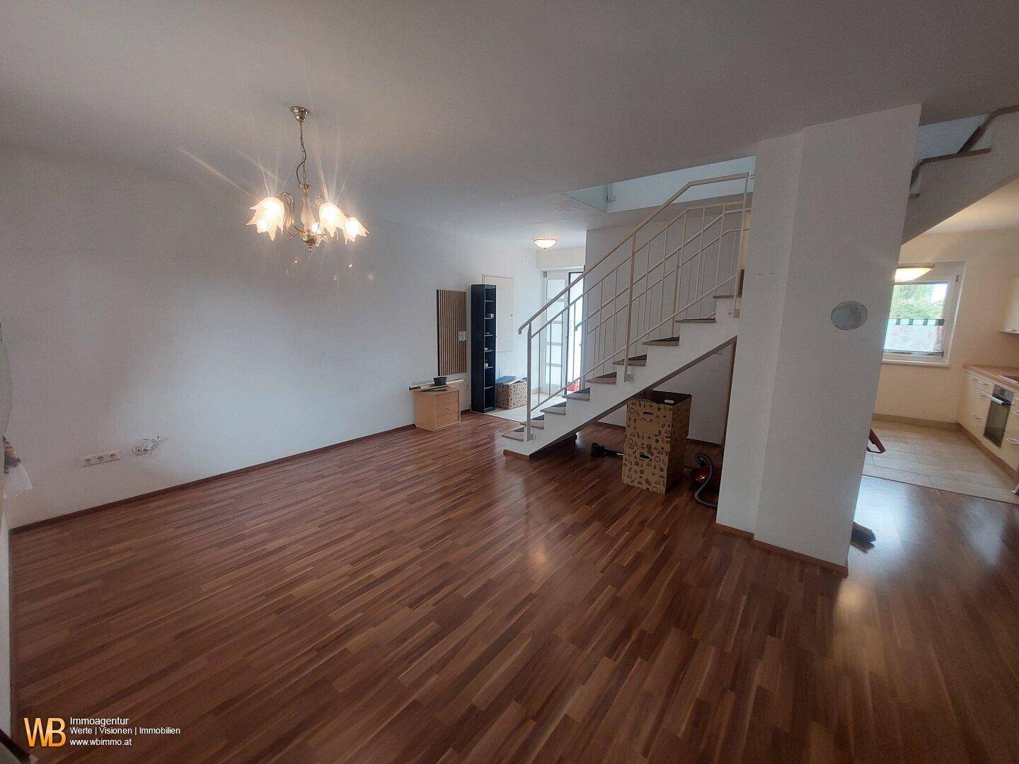 Offener Wohnbereich mit Holzfußboden, Eingangsbereich und Blick in die Küche.
