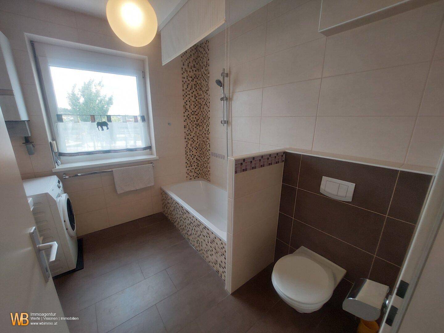 Badezimmer mit Badewanne, Dusche und Wand-WC.