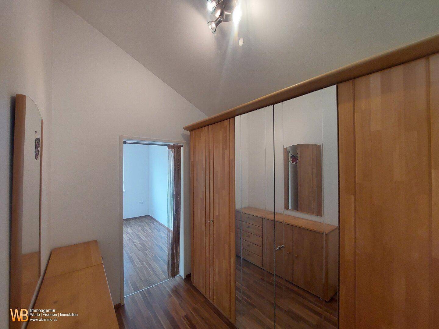 Flur oder Ankleidebereich mit Holzfußboden und großem Spiegelschrank.